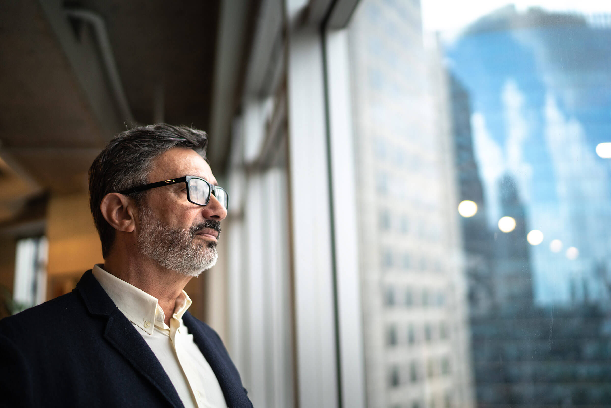 Close-up of middle-aged professional male standing in a building thoughtfully peering out the window